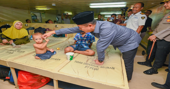 Gubernur NTB, Lalu Muhamad Iqbal saat memegang jari tangan bocah di sela-sela memantau kesiapan Posko Mudik, di Teluk Bima, pada Jumat malam (21/3/2025).