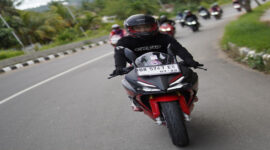 Pengendara saat mengendarai sepeda motor Honda di jalan raya. 
