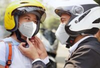 Sebelum membonceng anak, orang tua memasang helm untuk keselamatan berkendara.