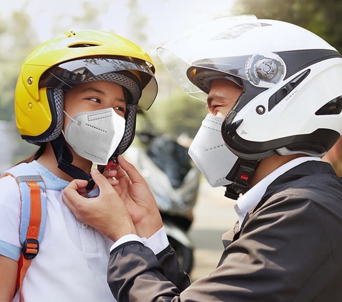 Sebelum membonceng anak, orang tua memasang helm untuk keselamatan berkendara.