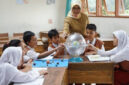 Terlihat ibu guru sedang fokus mengajar muridnya di  ruang kelas.