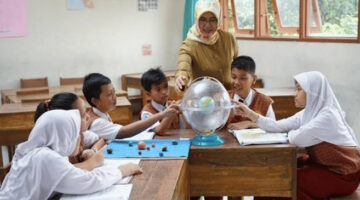 Terlihat ibu guru sedang fokus mengajar muridnya di  ruang kelas.