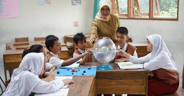 Terlihat ibu guru sedang fokus mengajar muridnya di  ruang kelas.