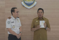 Bupati Lotim, H. Haerul Warisin saat menerima paspor perdana dari Kepala Kantor Imigrasi Lotim, Iqbal Rifai.